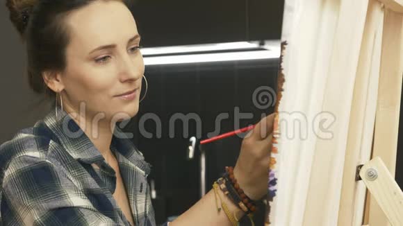 年轻受启发的女艺术家用丙烯酸涂料在画布上画画家里的女人画肖像布鲁内特天才g视频的预览图