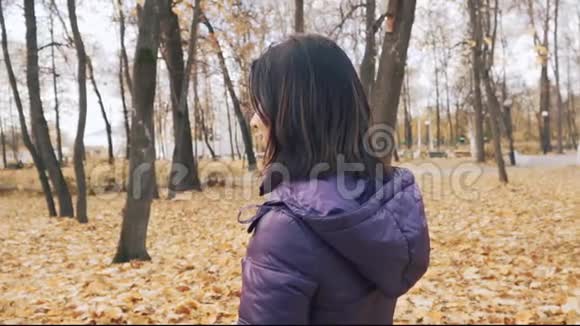 快乐的年轻漂亮的黑发女人正在公园里摆着一束秋叶视频的预览图