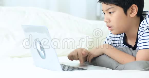 带笑脸笔记本电脑键盘上的尤特亚洲男孩手写打字机视频的预览图