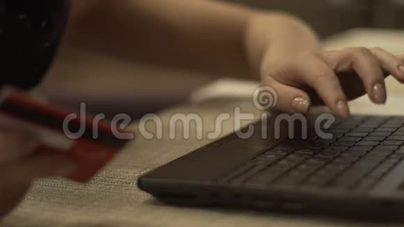 女性手拿银行卡用笔记本键盘打字在线支付视频的预览图