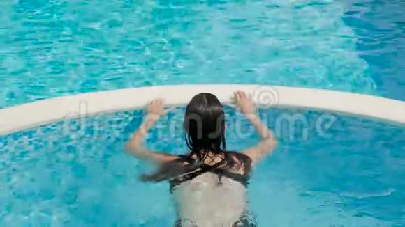 穿着黑色泳衣的女孩躺在街上的一个圆形游泳池里视频的预览图