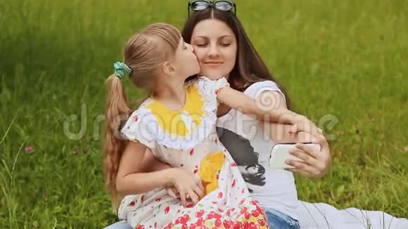 女孩亲吻她的妹妹他们在草地上自拍视频的预览图