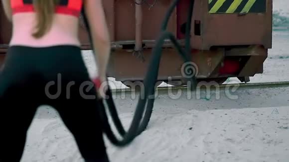 运动的女人在一根厚厚的运动的绳子的帮助下进行力量练习绳子的特写在黎明在视频的预览图