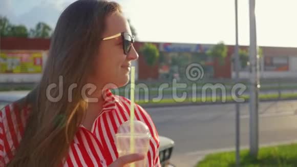 夏天穿红色衣服的年轻女孩的肖像女孩从稻草中喝酒视频的预览图