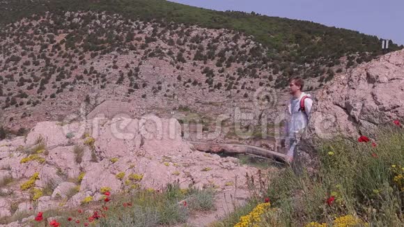 一个带着橙色背包的旅行者在山上漫步视频的预览图