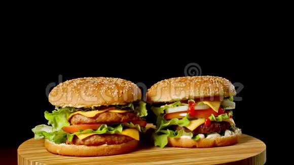 两个工艺牛肉汉堡在木桌上隔离在黑暗的灰度背景视频的预览图