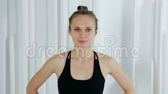 穿黑色衣服的瑜伽女孩站在白色工作室里视频的预览图