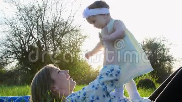 爱是最重要的在公园里在草地上在草坪上躺着妈妈一个年轻的金发女人在玩耍微笑着和视频的预览图