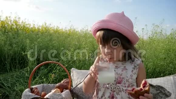 可爱的小女孩肖像喝牛奶吃面包日落时的牛角面包儿童野餐性质孩子家庭野餐视频的预览图