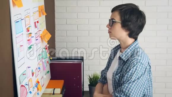 沮丧和压力的女UX设计师为新的项目想法而奋斗他的头站在白板上视频的预览图