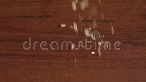 特写燕麦片慢地落在棕色的木桌上视频的预览图