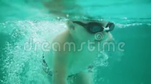 一个戴着防护眼镜的可爱金发幼儿在游泳池的水下游泳的镜头视频的预览图