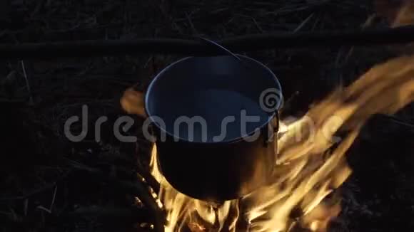 在森林里的篝火上做饭锅煮饭用的锅挂在火棒上4K视频的预览图