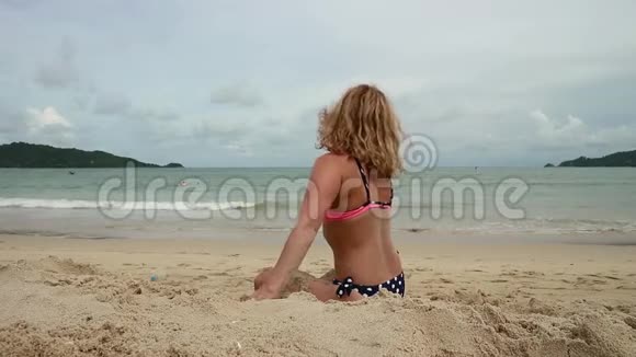 美丽苗条的女人在异国海滩玩沙视频的预览图