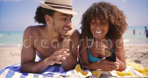 在海滩上听音乐和微笑的情侣视频的预览图
