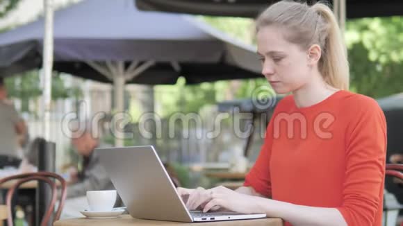 年轻女子坐在咖啡厅露台上做手提电脑视频的预览图