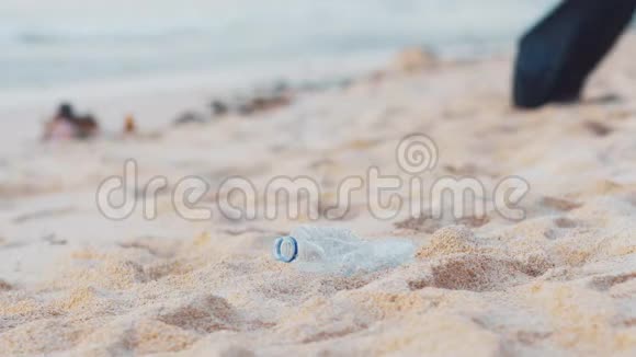 特写志愿者在白色的海洋海滩上捡起塑料瓶志愿者打扫海滩整理一下视频的预览图