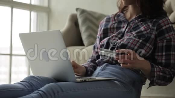 年轻女子坐在公寓里用银行卡支付购买费用视频的预览图