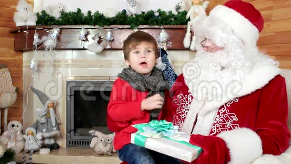 小男孩告诉圣诞老人他的圣诞愿望孩子坐在圣尼古拉斯大腿上给孩子的大礼物视频的预览图