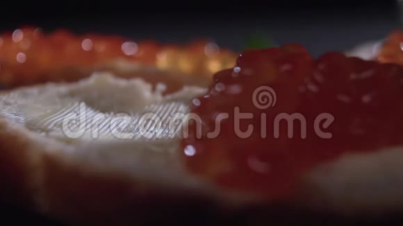 一个黑色的勺子把红色的鱼子酱放在一块面包上视频的预览图