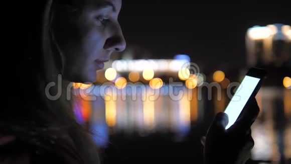 夜街妇女使用智能手机背景是夜城灯光视频的预览图