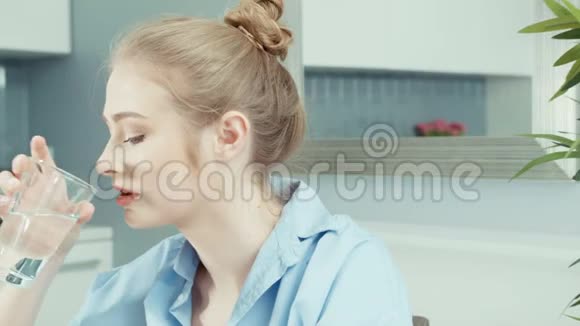 健康的年轻金发女人在家喝水的肖像视频的预览图