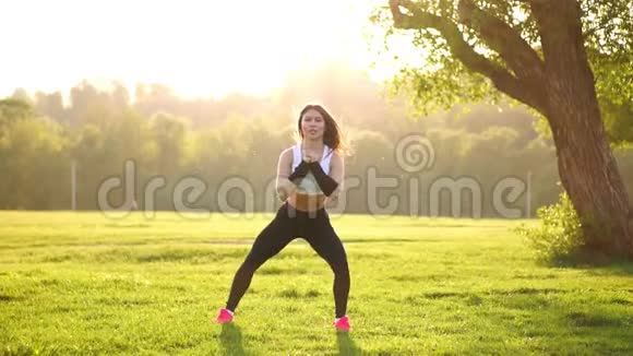 年轻的肌肉健身女子在大自然中做蹲式运动视频的预览图
