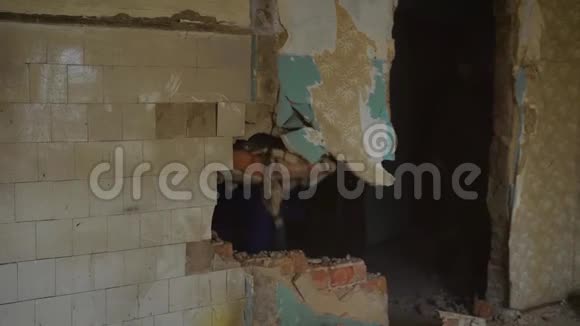专业建筑工人用大锤拆除一座旧建筑中的墙视频的预览图