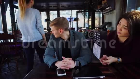 女朋友和男朋友手上戴着智能手表坐在桌子附近智能手机和笔记本电脑吵架视频的预览图