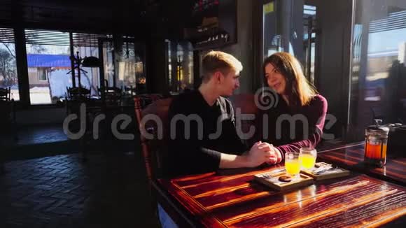 一对年轻的幸福夫妇坐在餐桌旁在咖啡馆里喝着沙棘汤讨论电影视频的预览图