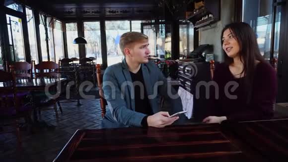 女友和男友带着智能手表讨论自己的咖啡屋的设计并用智能手机拍照视频的预览图