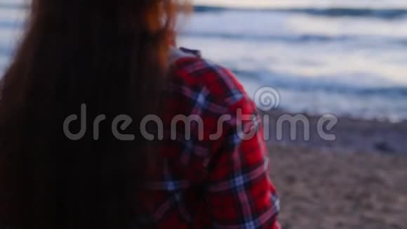 日落或日出时在海滩拍照的年轻女子视频的预览图