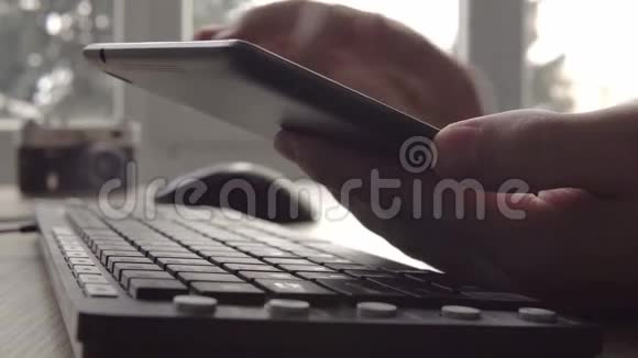在坐电脑键盘和鼠标的时候用平板电脑紧紧抓住年轻人的手自由摄影师视频的预览图