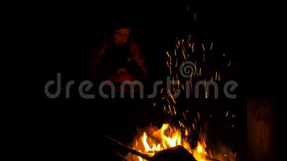 晚上在森林篝火旁带着智能手机的女孩视频的预览图