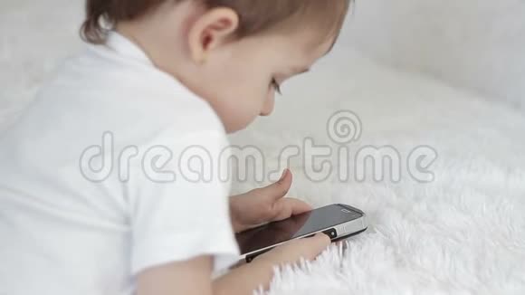 小孩躺在沙发上看着智能手机的电子显示屏视频的预览图