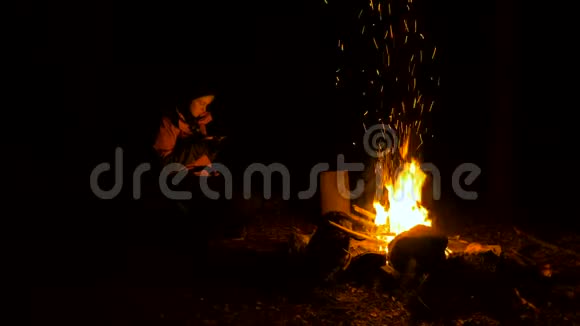 晚上在森林篝火旁带着智能手机的女孩视频的预览图