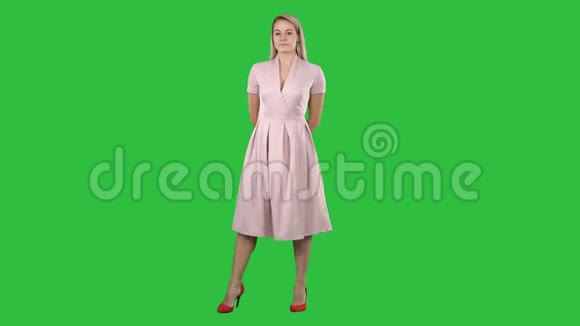 快乐美丽的女人穿着粉红色的连衣裙在绿色屏幕上摆姿势Chroma键视频的预览图