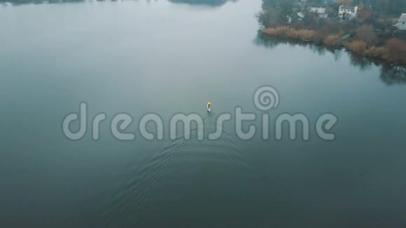 超板空中无人机镜头无人机飞在一个站起来的划水板上的人的上方秋天的森林视频的预览图
