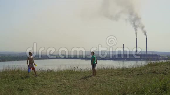 2017年乌克兰孩子们在热电厂的背景上玩耍晴朗的夏日黑烟蔓延视频的预览图
