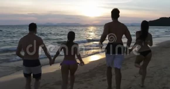 在海上奔跑的欢乐人群的后后景在夕阳下的沙滩上快乐的朋友视频的预览图