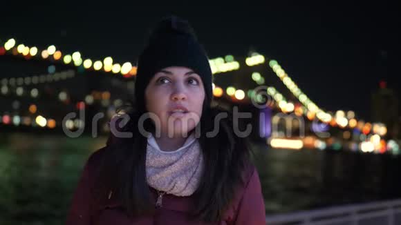 年轻女子晚上坐在纽约布鲁克林大桥上视频的预览图