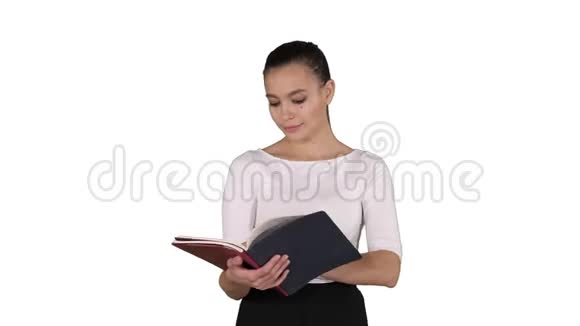 年轻的商务女性在白色背景下从笔记本上行走和阅读视频的预览图