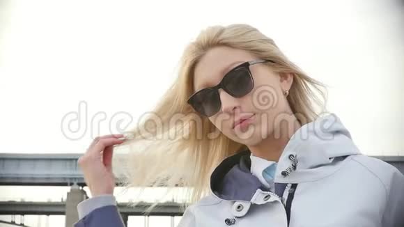 戴太阳镜的年轻美女在散步的时候金发美女慢动作视频的预览图