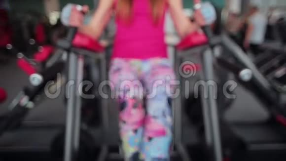 在一个体育俱乐部里一个女人在平行的酒吧里练习腿的动作在健身房锻炼视频的预览图