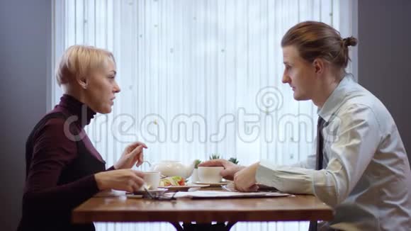 两个年轻人在咖啡馆里一起工作他们吃商务午餐餐馆里的女人和男人视频的预览图