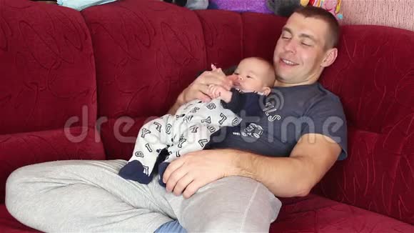 快乐的父亲带着一个婴儿撒谎并亲吻他视频的预览图