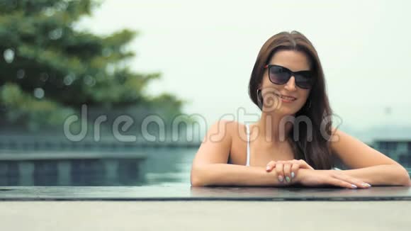 年轻漂亮的时尚女士在游泳池里摆着户外造型视频的预览图