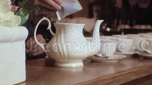 一个人把茶从水壶里倒进木桌上的白色杯子里视频的预览图