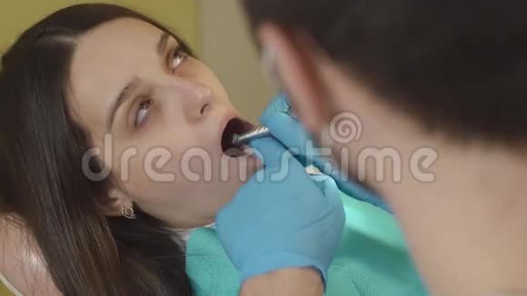 牙医在一个年轻女人的牙齿上钻特写视频的预览图