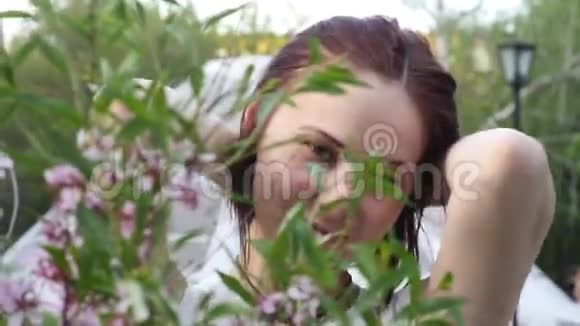 公园里一棵开花树附近的美丽女孩肖像青春和自然美的概念一个年轻的女孩视频的预览图